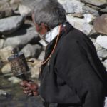 Photo of an older man / Fotografija starejšega gospoda z budističnim molilnim mlinčkom v roki