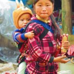 Photo of a big sister carrying her little brother / Fotografija deklice, ki na hrbtu nosi bratca (ali sestrico)