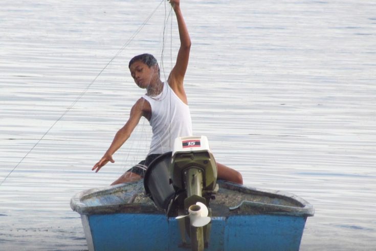 Photo of a boy fishing / Fotografija fanta na čolnu, ki lovi ribe
