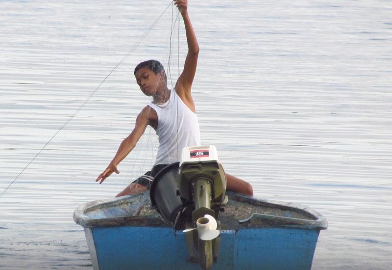 Photo of a boy fishing / Fotografija fanta na čolnu, ki lovi ribe